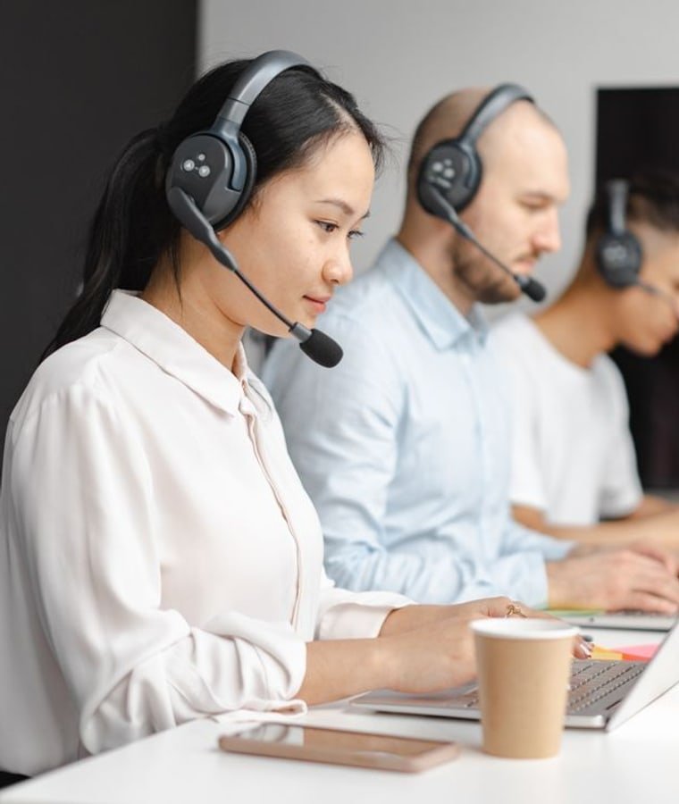 Support engineers working at laptops wearing headsets